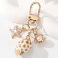 Dettaglio di un portachiavi con stella marina e conchiglia dorata con perla su base - Stile Lumaca di Mare Maculata (款式1)
