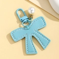 Close-up of sky blue faux leather bow keychain with pearl pendant and metal lobster clasp - Blue