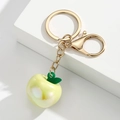 Detailaufnahme von durchsichtigem Apfel-Schlüsselanhänger mit goldener Kette und Verschluss - Gelb