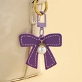 Détail d'un porte-clés nœud en cuir violet avec pendentif perle et accents de cristal brillant - Violet