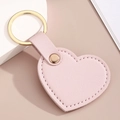 Vue détaillée du porte-clés cœur en cuir rose avec texture litchi et anneau doré - Rose