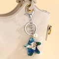 Portachiavi a stella marina in resina blu con conchiglie e perle su una borsa di pelle - Blu scuro