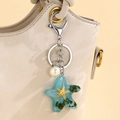 Portachiavi a stella marina in resina blu con perla bianca su borsa beige - Azzurro