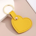 Vue détaillée du porte-clés cœur en similicuir jaune avec anneau doré et surpiqûres - Jaune