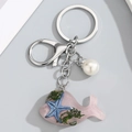Detalle del llavero de delfín rosa con estrella de mar y algas verdes internas - Rosa