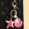 Detail of colorful resin starfish and seashell pendant on a quilted leather bag - Rose Red