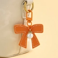 Detailansicht eines orangefarbenen Lederbogens mit weißer Perle und Metallhaken - Orange