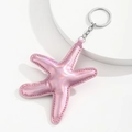 Macro detail of a light pink laser PU leather starfish keychain with silver metal ring - Pink