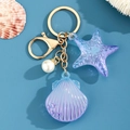 Detalle del llavero de estrella de mar y concha de acrílico azul con cierre dorado y perla - Azul y Púrpura