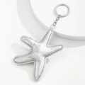 Detail of silver holographic starfish keychain with fine stitching on white platform - Silver