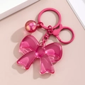 Detailansicht eines rosa Acryl-Schleifenanhängers mit Glitzerkugel und Metallschlüsselbund - Rosarot