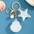 Detalle de llavero marino creativo con concha, estrella de mar y perla en metal dorado - Blanco
