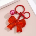 Detail view of red translucent resin bow keychain with shiny glitter ball charm - Red