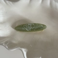 Detalle de una pinza ovalada verde para el pelo con purpurina en un plato blanco - Pinza para el Cabello Verde Curvada / Verde