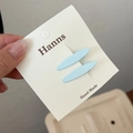 Detalle de pinzas ovaladas de metal azul claro en una tarjeta de presentación blanca - Diseño Ovalado / Azul