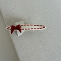 Detail of a red bow hair clip with dotted edges and polished enamel finish - Creamy White Oval Clip With Single Bow
