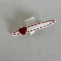 Detail of a white oval hair clip with red dotted edges and a 3D heart on fabric - Creamy White Oval Clip With Red Heart