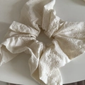 Gros plan d'un chouchou blanc avec broderie florale délicate et détails de texture - Nœud Blanc