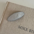 Detail of silver glitter oval hair clip with gray stitched edges on beige canvas background - Silver Oval (10#)