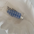 Détail d'une pince à cheveux à carreaux bleus et blancs sur une étiquette vintage - Barrette Goutte d'Eau Bleue