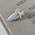 Détail de la pince à cheveux florale avec nœud en perles sur fond en lin beige - Barrette Trapèze Florale Bleue Nœud Perle