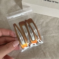 Close-up of three amber tortoiseshell teardrop hair clips with metal base in hand - Tortoiseshell Triangle Style