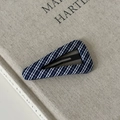 Détail d'une pince à cheveux BB à carreaux bleus et blancs sur une couverture de livre - Barrette triangulaire en tissu à petits carreaux bleus