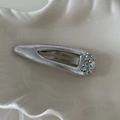 Dettaglio di un fermaglio per capelli a fiori argentati con strass blu su vassoio - Fermaglio a Goccia Svuotata Argento con Due Fiori