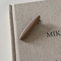 Detail view of a vintage brown plaid fabric hair clip resting on a textured linen book - Coffee Thick Curved Hair Clip