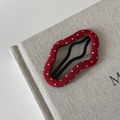 Detailed view of wave-shaped red hair clip with white polka dots on linen background - Red Cloud White Dot Hair Clip