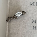 Detailed view of the brown plaid fabric texture and oval button on this hair clip - Coffee Wave Bow