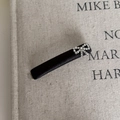 Detail of black satin hair clip with sparkling rhinestone bow on textured linen background - Slender Black Bow