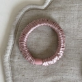Dettaglio di elastico rosa in raso con trama elastica su un tappetino di lino beige - modello base / Rosa