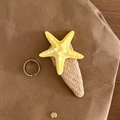 Detailansicht einer gelben Seestern-Haarklammer und eines silbernen Rings auf Kraftpapier - Gelb