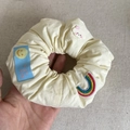 Detail of yellow fabric hair scrunchie with rainbow embroidery and a cloud charm - Rainbow (White)