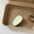 Detail view of cream-colored teardrop hair clip and adjustable silver ring in wood tray - White Waterdrop Blue Stripe Clip