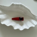Detail of a red snap hair clip with a purple heart resin charm in a shell tray - Red Teardrop Clip With Black Heart