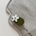 Close-up of olive green hair clip with matte white flower and sparkling rhinestone center - Clear Flower Green Clip