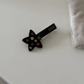 Detalle de horquilla de estrella con pedrería de colores y el logo de la marca - Estilo Estrella Negra Diamantes Coloridos