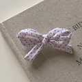 Vue détaillée de la pince à cheveux à pois rouges style français sur un livre rétro - Blanc à pois rouges / Blanc