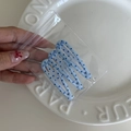 Detailopname van blauwe stippen BB-haarspelden in de hand boven een witte keramische plaat - Blauw Donkerblauw Stippenpatroon Stijl
