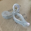 Close-up of light blue pearlescent bow hair claw clip on canvas background with soft lighting - Transparent Blue