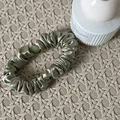 Elegante scrunchie in raso verde oliva su sfondo intrecciato per uno styling chic - Increspato / Verde