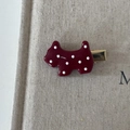 Detailed close-up of a burgundy polka dot Scottie dog hair clip on beige linen fabric - Dog Shaped Hairpin
