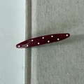 Close-up of a vintage dark red polka dot hair clip with a smooth glossy resin finish - Wave Hairpin