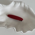 Gros plan sur une barrette en tissu rouge texturé posée sur un plateau en forme de coquille - Barrette Arc Rouge Uni (2#)