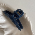 Détail d'une pince à cheveux mate bleu marine avec ressort en métal doré sur plateau - Bleu