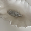 Macro shot of silver-toned hair clip with sparkling crystals on white shell tray - White Crystal Hair Clip