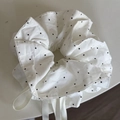 Close-up of a white polka dot scrunchie with soft fabric texture and decorative ribbons - White Polka Dot Drawstring Scrunchie