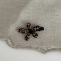 Detailweergave van Franse bloemhaarklem met luipaardprint op getextureerd linnen - Luipaardbloem Haarspeld